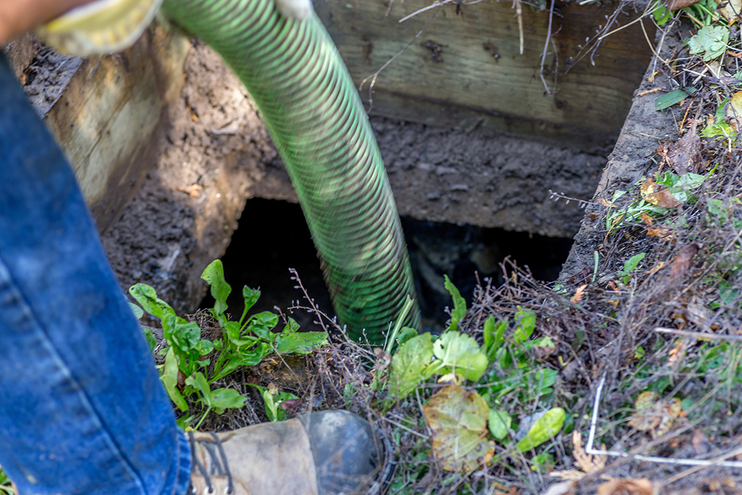 Man holding tube over septic tank